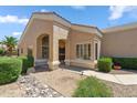 Beige single-story home featuring a covered front entrance and desert landscaping at 8426 W Utopia Rd, Peoria, AZ 85382
