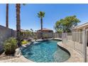Private backyard oasis with a sparkling pool, rock waterfall feature, and lush landscaping at 10557 W Louise Dr, Peoria, AZ 85383