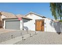 Inviting home featuring a gray garage door, a wood gate, and desert landscaping at 13320 N 82Nd Dr, Peoria, AZ 85381