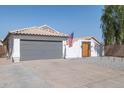 Beautiful single-story home showcasing a gray garage door, white exterior, and tiled roof at 13320 N 82Nd Dr, Peoria, AZ 85381
