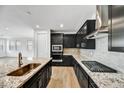 Modern kitchen featuring dark cabinets, granite countertops, stainless steel appliances and island with sink at 18950 W Stella Ave, Waddell, AZ 85355