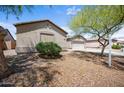 Beautiful exterior showcasing desert landscaping with a three car garage and a lush green bush at 22926 W Yavapai St, Buckeye, AZ 85326