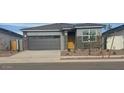 Charming single-story home featuring a gray exterior, gray garage door, and low maintenance landscaping at 25235 N 183Rd Dr, Wittmann, AZ 85361