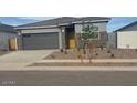 Charming single-story home featuring a gray exterior, gray garage door, and low maintenance landscaping at 25235 N 183Rd Dr, Wittmann, AZ 85361