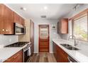 Well-lit kitchen featuring wooden cabinets, stainless steel appliances, and a double basin sink at 3031 E Avalon Dr, Phoenix, AZ 85016