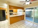 Bright kitchen with black appliances, breakfast bar, tile floors, and sliding doors to backyard at 924 S Hacienda Dr # C, Tempe, AZ 85281