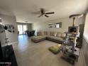 Spacious living room featuring tile flooring, a comfortable sectional sofa, ceiling fan, and a cat tower at 2007 N 55Th Ln, Phoenix, AZ 85035