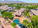 Aerial view of a backyard with a sparkling pool, mature landscaping, hot tub and an umbrella-covered patio at 20639 W Grandview Dr, Buckeye, AZ 85396