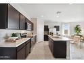 Contemporary kitchen featuring dark cabinetry, stainless steel appliances, a marble island, and an adjacent dining area at 1331 S Vista Ave, Florence, AZ 85132