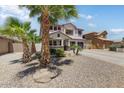 Charming two-story home showcasing a well-manicured desert landscape, palm trees and a three car garage at 14878 W Windrose Dr, Surprise, AZ 85379