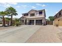 Charming two-story home showcasing a well-manicured desert landscape, palm trees and a three car garage at 14878 W Windrose Dr, Surprise, AZ 85379