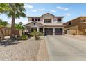 Charming two-story home showcasing a well-manicured desert landscape, palm trees and a three car garage at 14878 W Windrose Dr, Surprise, AZ 85379