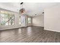 Open living room featuring wood look tile floors, a modern light fixture, and bright natural light at 2409 W Red Range Way, Phoenix, AZ 85085