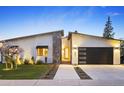 Contemporary home showcasing a modern facade with a stone accent, a black garage door and desert landscaping at 4002 N 33Rd Pl, Phoenix, AZ 85018