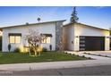 Charming home featuring drought resistant landscaping, a stone accent and a black modern garage door at 4002 N 33Rd Pl, Phoenix, AZ 85018