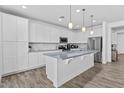 Modern kitchen with white cabinetry, stainless steel appliances, and an island with pendant lighting at 40990 W Agave Rd, Maricopa, AZ 85138
