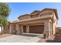 Inviting tan two-story home featuring a covered two-car driveway, desert landscaping, and a neutral color scheme at 44859 W Sage Brush Dr, Maricopa, AZ 85139