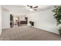 Spacious living room with neutral carpeting, ceiling fan, and open floorplan leading to dining and kitchen at 815 W El Prado Rd, Chandler, AZ 85225