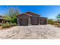 A three-car garage stands at the end of a paved driveway, showcasing the building's wooden details at 8555 E Tecolote Cir, Scottsdale, AZ 85266