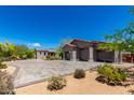 The large three-car garage features a tile roof and paved parking area, surrounded by desert landscaping at 8555 E Tecolote Cir, Scottsdale, AZ 85266