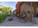 Inviting outdoor patio with unique hanging chairs, a fire pit, and lush desert landscaping at 9502 N 47Th St, Phoenix, AZ 85028