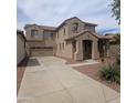 Two-story home with neutral-toned exterior, desert landscaping, and wide driveway leading to a two-car garage at 15446 W Jenan Dr, Surprise, AZ 85379