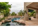Backyard pool with a waterfall feature, tropical landscaping, and a covered patio at 21614 N 59Th Ln, Glendale, AZ 85308