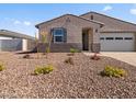 Tan single story home featuring colorful flowers, neutral landscaping, and an attached two-car garage at 24486 W Grenadine Rd, Buckeye, AZ 85326