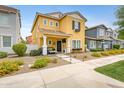 Charming two-story home featuring a yellow facade, manicured landscaping, and a welcoming front porch with seating at 1316 S Minneola Ln, Gilbert, AZ 85296