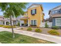 Charming two-story home featuring a yellow facade, manicured landscaping, and a welcoming front porch with seating at 1316 S Minneola Ln, Gilbert, AZ 85296