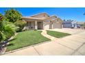 Inviting single-story home with a covered porch, two-car garage, and lush green lawn at 14298 W Amelia Ave, Goodyear, AZ 85395