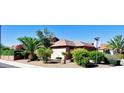 Desert home with a tiled roof and lush landscaping including palm trees at 18166 W Camino Real Dr, Surprise, AZ 85374