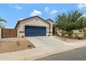 Charming one-story home featuring a blue garage door, desert landscaping, and a welcoming entrance at 18366 N Arbor Dr, Maricopa, AZ 85138