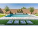 Backyard pool surrounded by lush green turf, decorative pavers, a brick wall, and beautiful landscaping at 3260 W Caleb Rd, Phoenix, AZ 85083