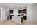 Bright kitchen showcasing a spacious island, stainless steel appliances, granite countertops, and sleek, dark cabinetry at 42900 W Peters Dr, Maricopa, AZ 85138