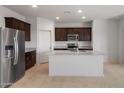 Modern kitchen featuring stainless steel appliances, a large island, granite countertops, and dark wood cabinetry at 42900 W Peters Dr, Maricopa, AZ 85138
