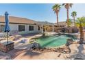 An inviting backyard pool area with a built-in grill, patio, and lush palm trees at 13630 W Redfield Rd, Surprise, AZ 85379
