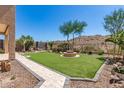 Expansive backyard featuring manicured artificial turf, desert landscaping, and a stone fire pit at 18547 W Sweet Acacia Dr, Goodyear, AZ 85338