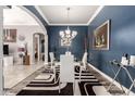 Elegant dining room with blue walls, a modern chandelier, and a glass table at 18547 W Sweet Acacia Dr, Goodyear, AZ 85338