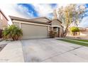 Beige single-story home featuring brick accents, a two-car garage, and desert landscaping at 28232 N Abby Cir, San Tan Valley, AZ 85143
