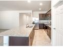 Open-concept kitchen features a granite island, stainless appliances, and dark wood cabinetry at 42960 W Palo Amarillo Rd, Maricopa, AZ 85138