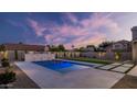 Backyard pool featuring custom stone waterfall and lush landscaping with a beautiful sunset at 5103 E Juniper Ave, Scottsdale, AZ 85254