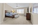 Spacious main bedroom with a plush bed, ceiling fan, large window, and comfortable furnishings at 12214 W Madison St, Avondale, AZ 85323