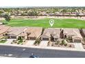 Aerial view of a well-maintained neighborhood showcasing lush green golf course, desert landscaping, and tile roof homes at 16077 W Vale Dr, Goodyear, AZ 85395
