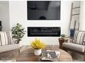 Comfortable living room featuring a fireplace, flat screen tv and stylish mid-century modern chairs and accessories at 20 S Buena Vista Ave # 111, Gilbert, AZ 85296
