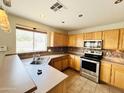 Well-lit kitchen with stainless steel appliances, tile backsplash, and ample counter space for meal preparation at 22311 W Woodlands Ave, Buckeye, AZ 85326