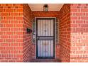 Close-up of the red-brick entrance featuring a secure screen door and vintage light fixture at 3115 N 26Th St, Phoenix, AZ 85016