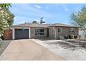 Single-story home with a gray brick exterior, a dark gray garage door, and a desert landscaped front yard at 3837 E Yale St, Phoenix, AZ 85008