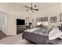 Cozy bedroom with neutral carpet, ceiling fan, large window, and furniture including desk and dresser at 43803 W Wade Dr, Maricopa, AZ 85138