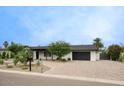 Beautiful home with a circular driveway, desert landscaping, and a modern black garage door at 5441 E Wethersfield Rd, Scottsdale, AZ 85254